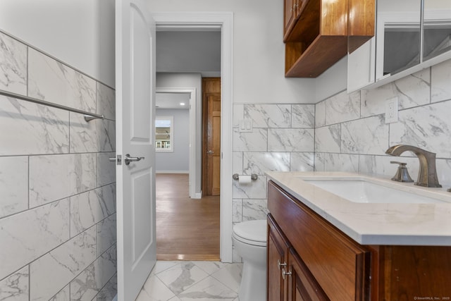 bathroom featuring vanity, tile walls, and toilet