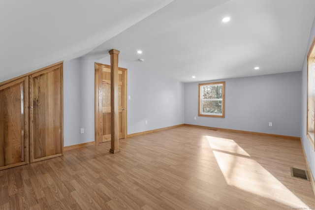 unfurnished living room featuring decorative columns, vaulted ceiling, and light wood-type flooring