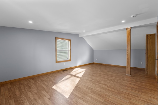 additional living space with ornate columns, vaulted ceiling, and light hardwood / wood-style flooring