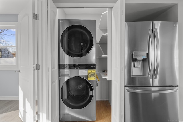 laundry room with stacked washer and dryer and light hardwood / wood-style flooring