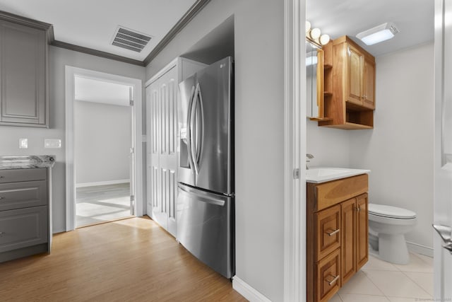 kitchen featuring sink, ornamental molding, light hardwood / wood-style floors, and stainless steel refrigerator with ice dispenser