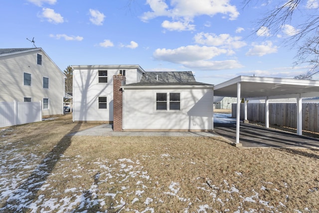 snow covered rear of property featuring a carport