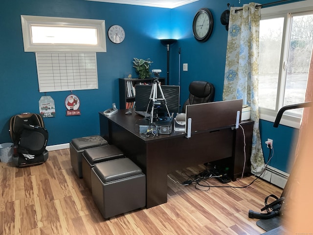 home office with a baseboard radiator, a wealth of natural light, and light hardwood / wood-style flooring