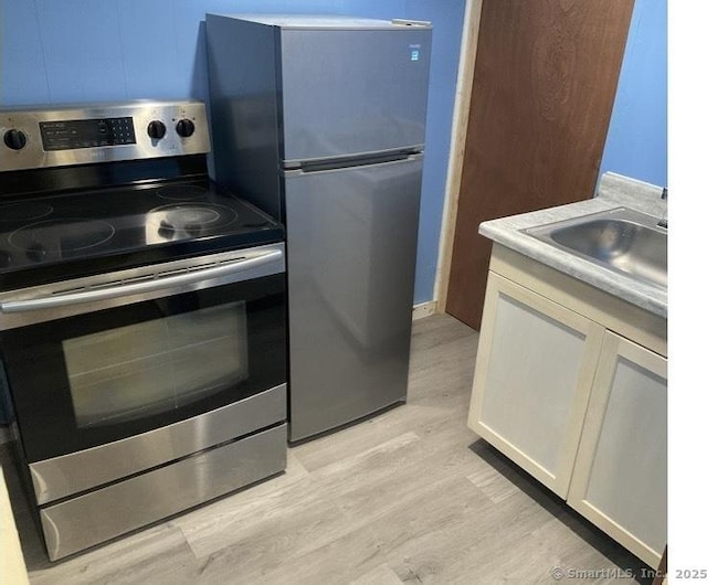 kitchen featuring sink, light hardwood / wood-style flooring, white cabinets, and appliances with stainless steel finishes