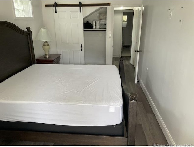 bedroom featuring a barn door, dark hardwood / wood-style floors, and a closet