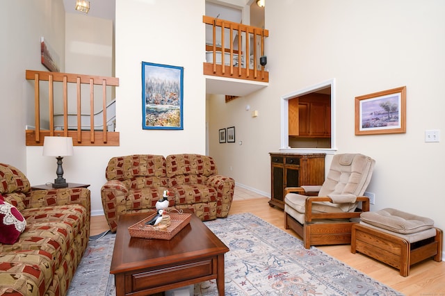 living room featuring a towering ceiling and light wood-type flooring