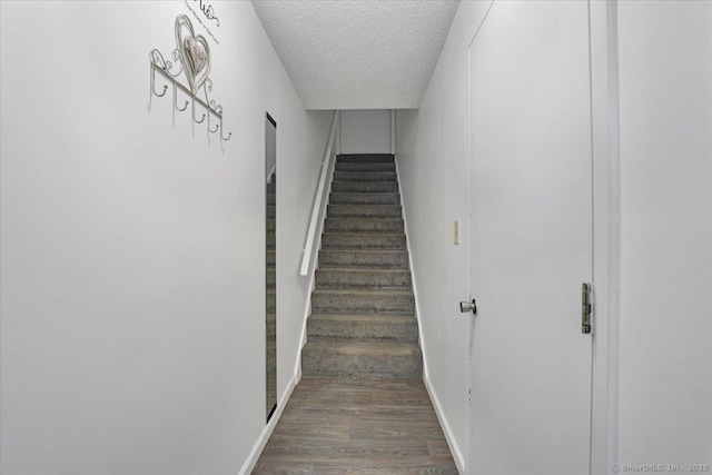 stairs with hardwood / wood-style flooring and a textured ceiling