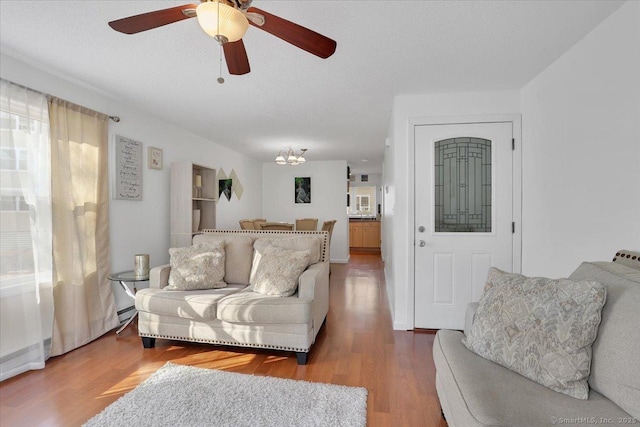 living room with ceiling fan, wood-type flooring, and a textured ceiling