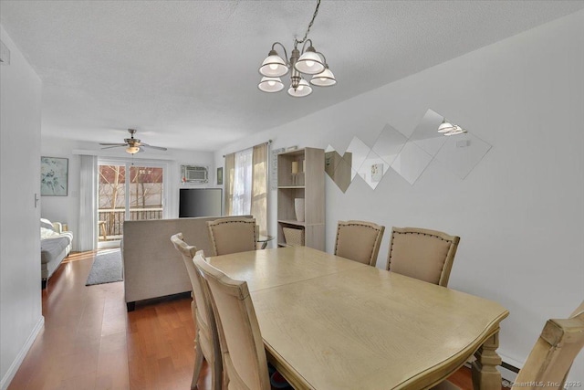 dining space featuring dark wood-type flooring, ceiling fan with notable chandelier, and a textured ceiling