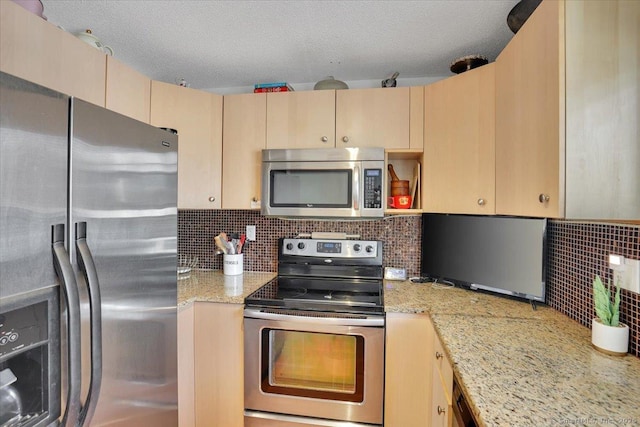 kitchen with light stone counters, stainless steel appliances, light brown cabinetry, and backsplash