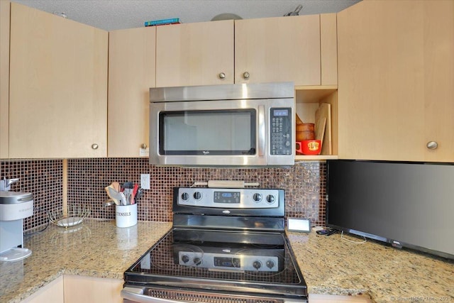 kitchen with light stone counters, stainless steel appliances, light brown cabinets, and backsplash