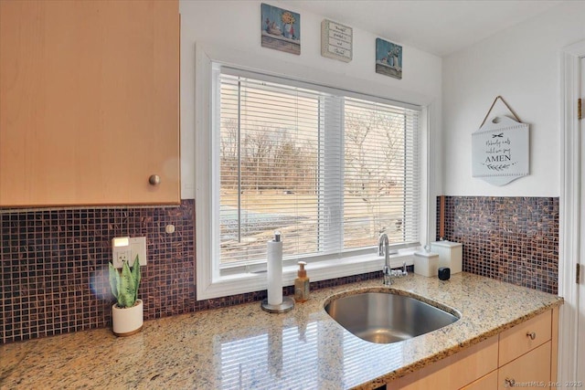 kitchen with light stone counters, sink, tasteful backsplash, and light brown cabinets