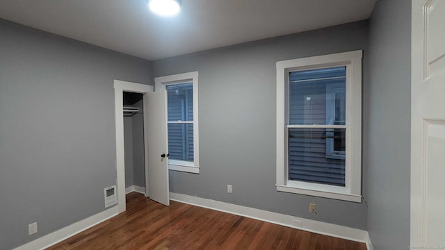 unfurnished bedroom with dark wood-type flooring and a closet