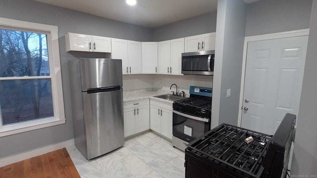 kitchen with appliances with stainless steel finishes, sink, and white cabinets