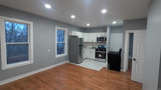 kitchen with white cabinetry, sink, light hardwood / wood-style floors, and appliances with stainless steel finishes