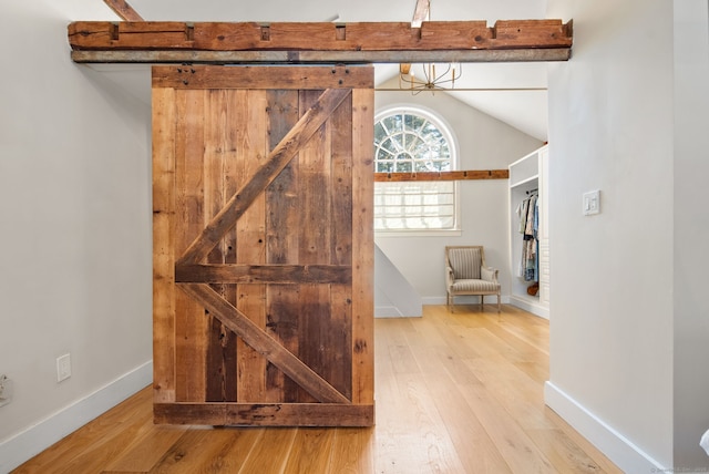 interior space featuring vaulted ceiling, a barn door, and hardwood / wood-style floors