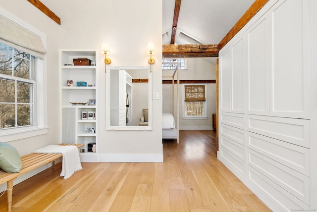 walk in closet featuring vaulted ceiling with beams and light hardwood / wood-style flooring