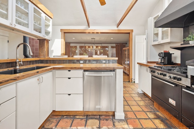 kitchen with range with gas stovetop, decorative light fixtures, sink, white cabinets, and wall chimney range hood