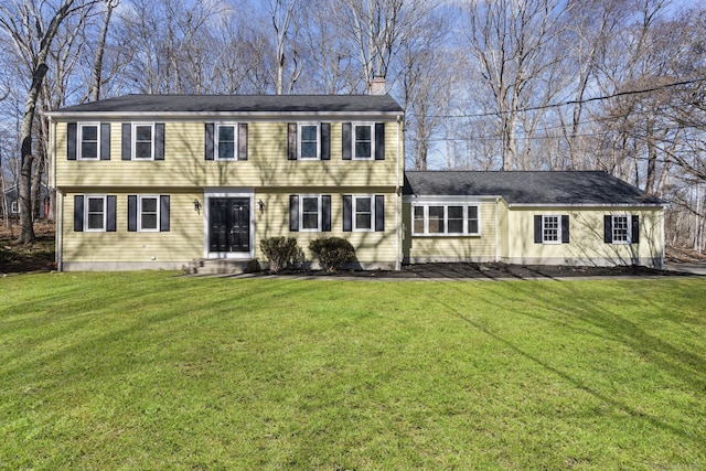 colonial-style house with a front yard, a chimney, and entry steps