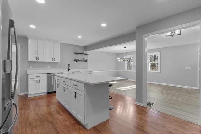 kitchen with stainless steel appliances, wood finished floors, visible vents, light countertops, and open shelves