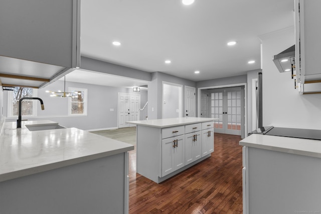 kitchen featuring a center island, french doors, dark wood finished floors, light countertops, and a sink