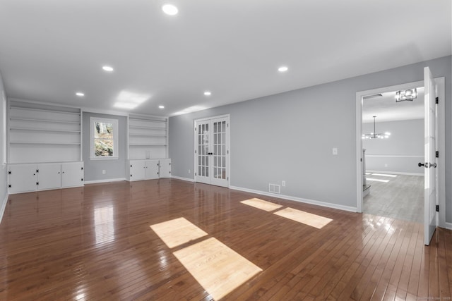 unfurnished living room with a chandelier, recessed lighting, baseboards, and hardwood / wood-style floors