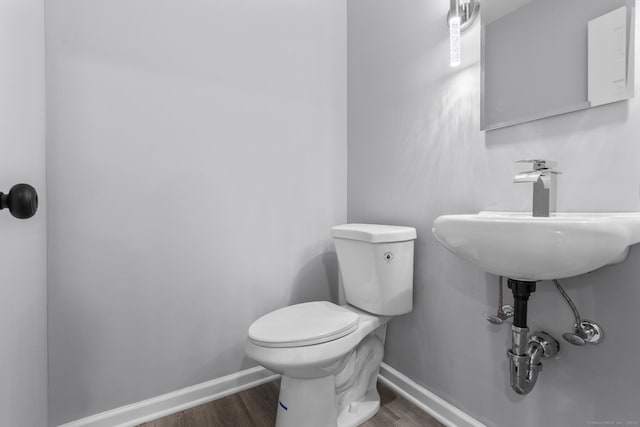 half bath with wood finished floors, toilet, and baseboards