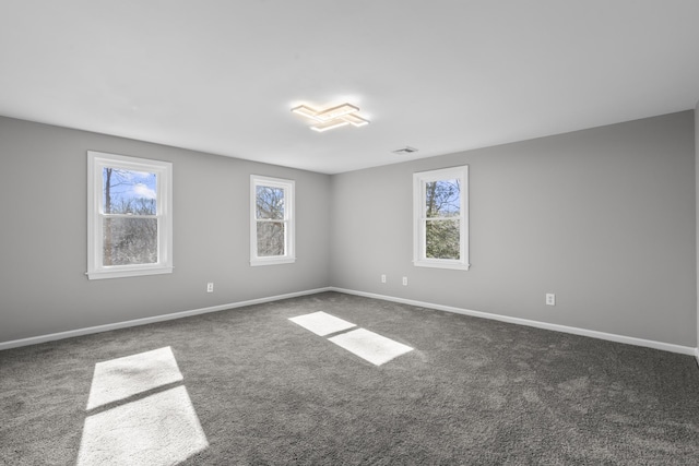 carpeted spare room with visible vents and baseboards