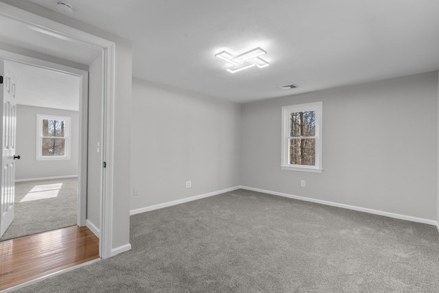 empty room featuring carpet, visible vents, and baseboards