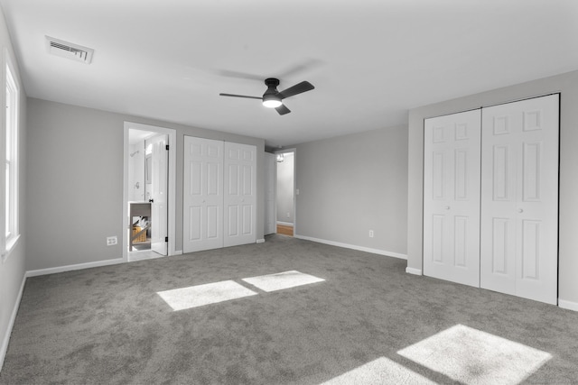 unfurnished bedroom featuring baseboards, carpet flooring, visible vents, and multiple closets