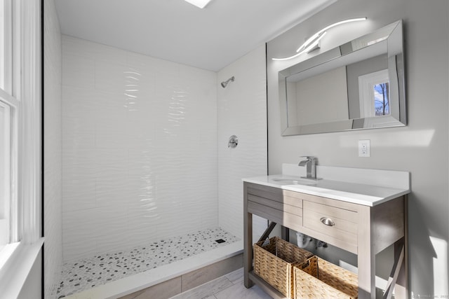 full bathroom featuring a tile shower and vanity