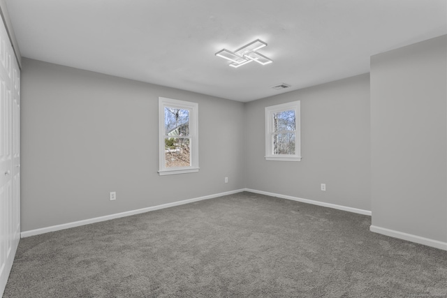 unfurnished room featuring carpet, visible vents, and baseboards