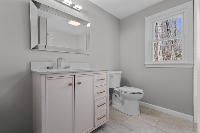 bathroom with baseboards, vanity, and toilet