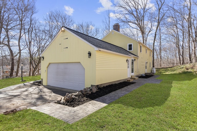 view of side of home with aphalt driveway, entry steps, a yard, and a chimney