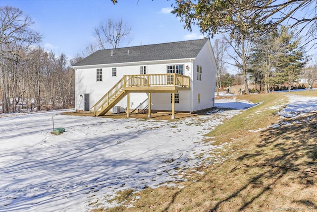 snow covered rear of property with central AC and a deck