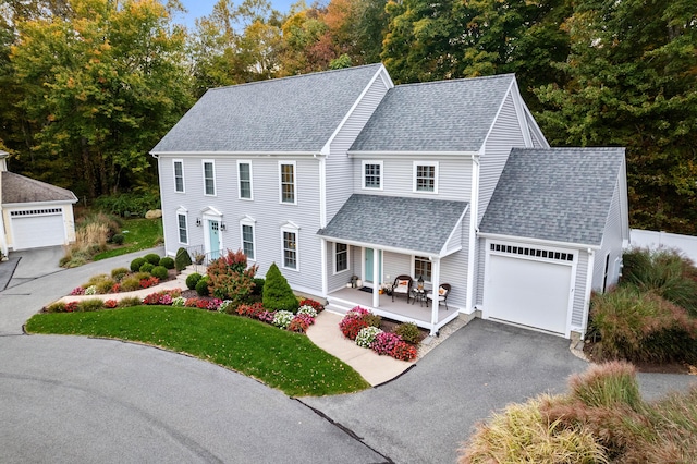 view of front of property featuring a garage, covered porch, and a front lawn