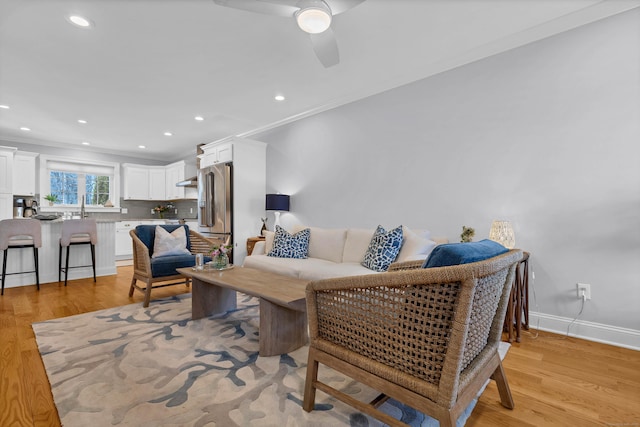 living room with crown molding, light hardwood / wood-style flooring, and ceiling fan