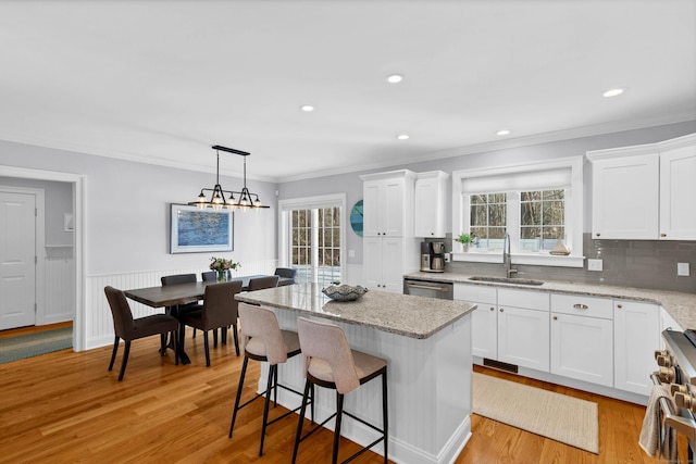 kitchen with pendant lighting, sink, white cabinetry, stainless steel appliances, and a center island