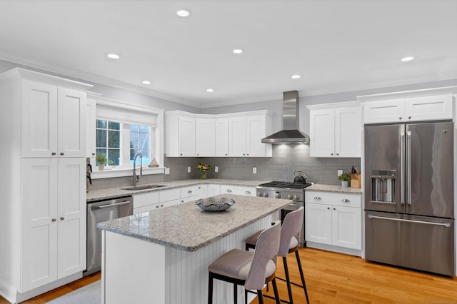 kitchen featuring sink, a breakfast bar area, premium appliances, a kitchen island, and wall chimney range hood