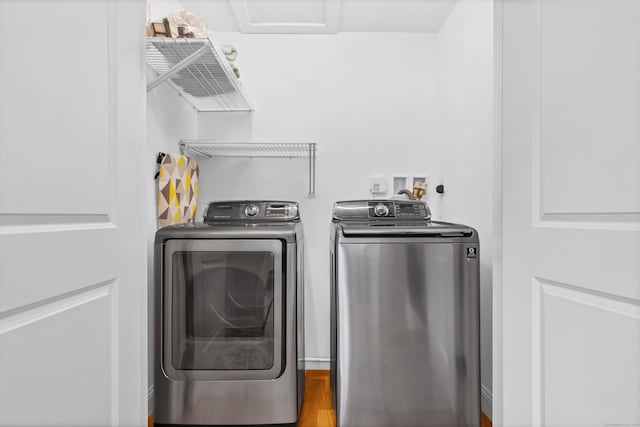 clothes washing area featuring hardwood / wood-style flooring and washer and clothes dryer