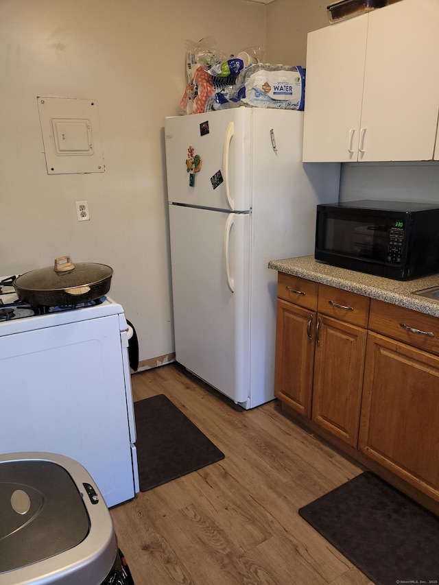 kitchen with white appliances and light hardwood / wood-style flooring