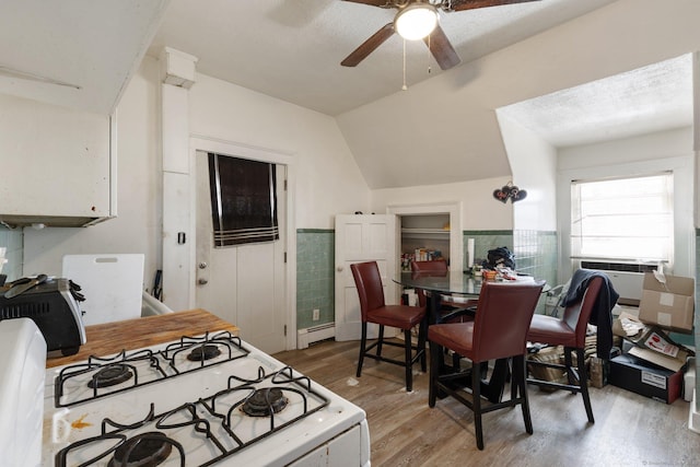 kitchen featuring vaulted ceiling, light hardwood / wood-style flooring, baseboard heating, ceiling fan, and white gas range oven