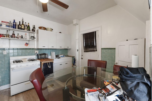 dining space featuring lofted ceiling, sink, ceiling fan, tile walls, and hardwood / wood-style floors