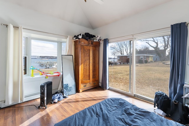 bedroom featuring vaulted ceiling, baseboard heating, hardwood / wood-style floors, a water view, and access to outside