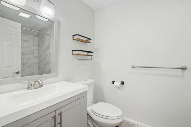 bathroom featuring vanity, tiled shower, and toilet