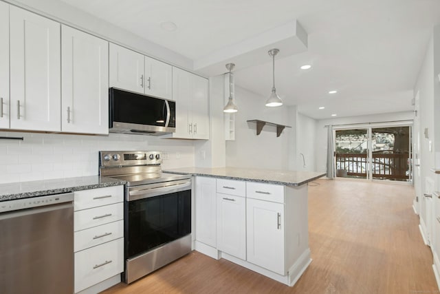 kitchen with pendant lighting, appliances with stainless steel finishes, white cabinetry, kitchen peninsula, and light wood-type flooring