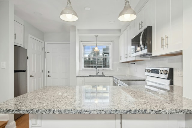 kitchen featuring white cabinetry, sink, stainless steel appliances, and kitchen peninsula