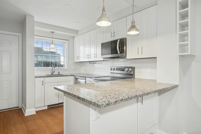 kitchen with sink, white cabinetry, hanging light fixtures, kitchen peninsula, and stainless steel appliances