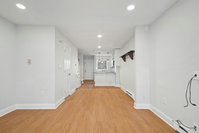 corridor featuring a baseboard heating unit and light wood-type flooring