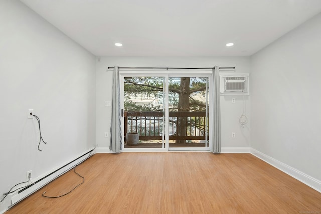 spare room with a wall mounted air conditioner, light hardwood / wood-style flooring, and a baseboard heating unit